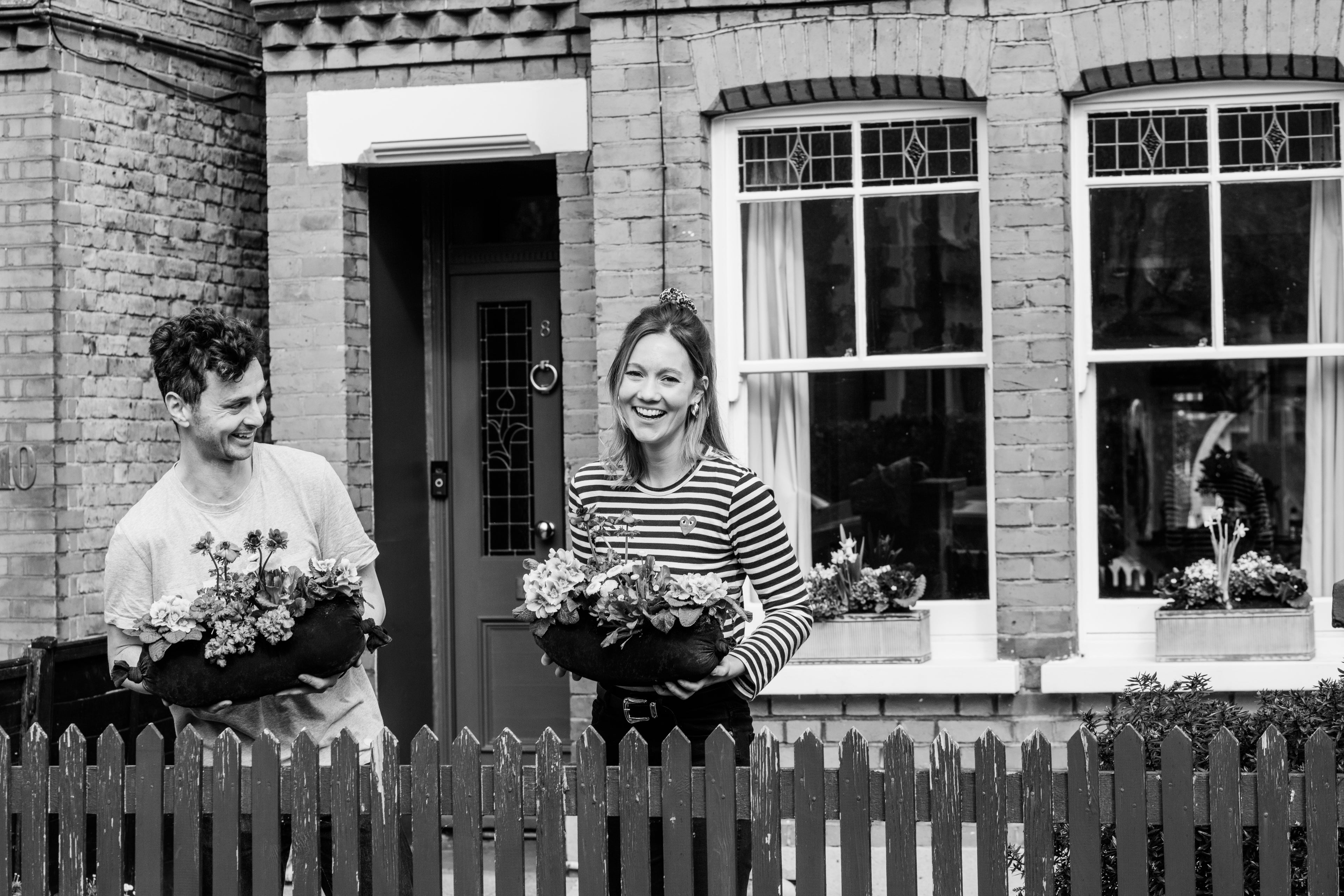 Man and woman with fresh planted flowers outside a terrace house
