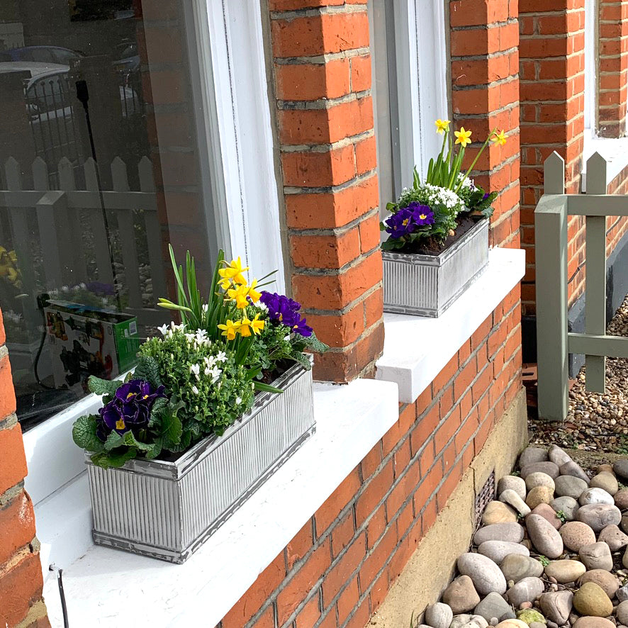 2 planted window boxes on a red brick window