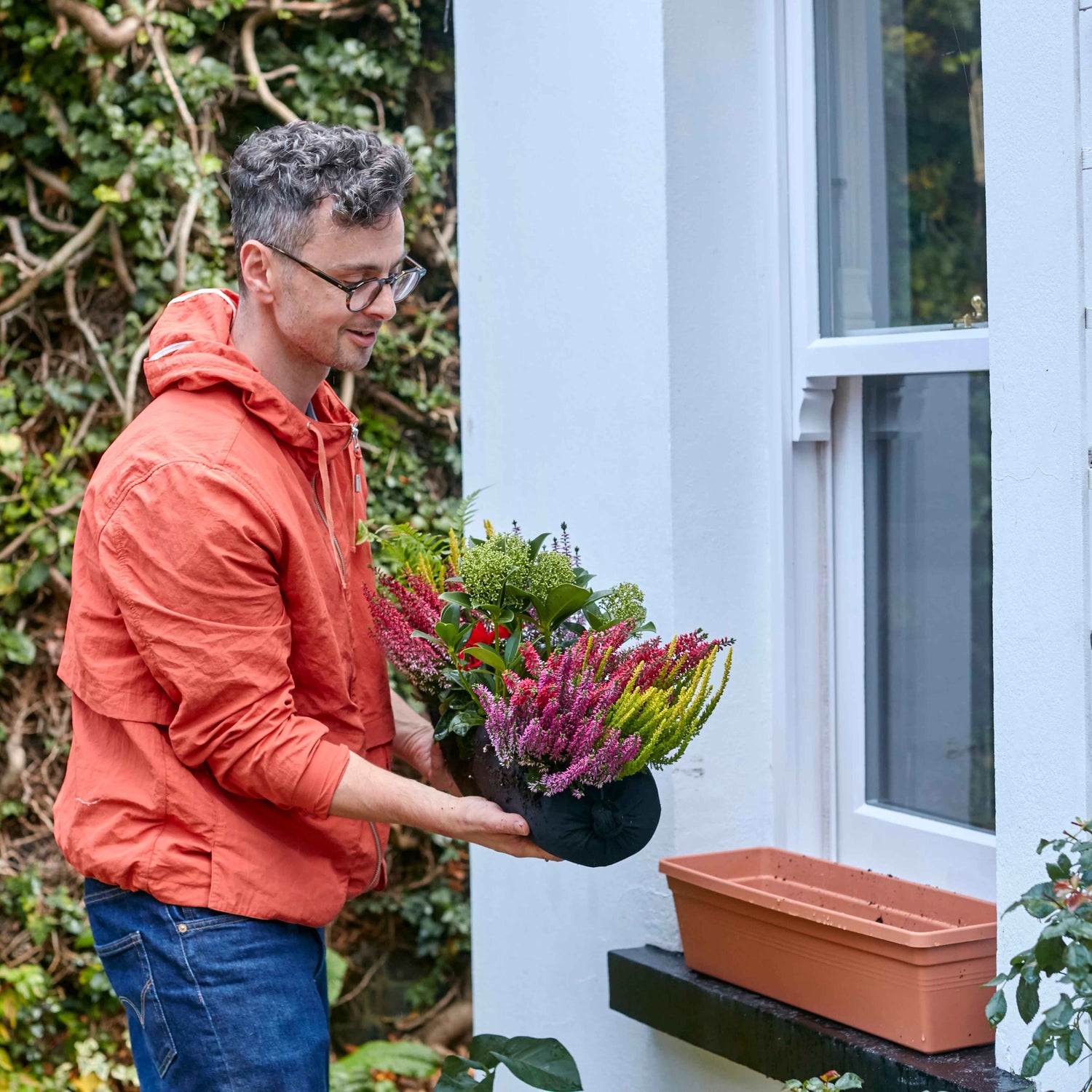 Man planting flowers in a window box