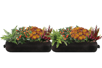 Two black fabric planters filled with flowers and greenery on a white background