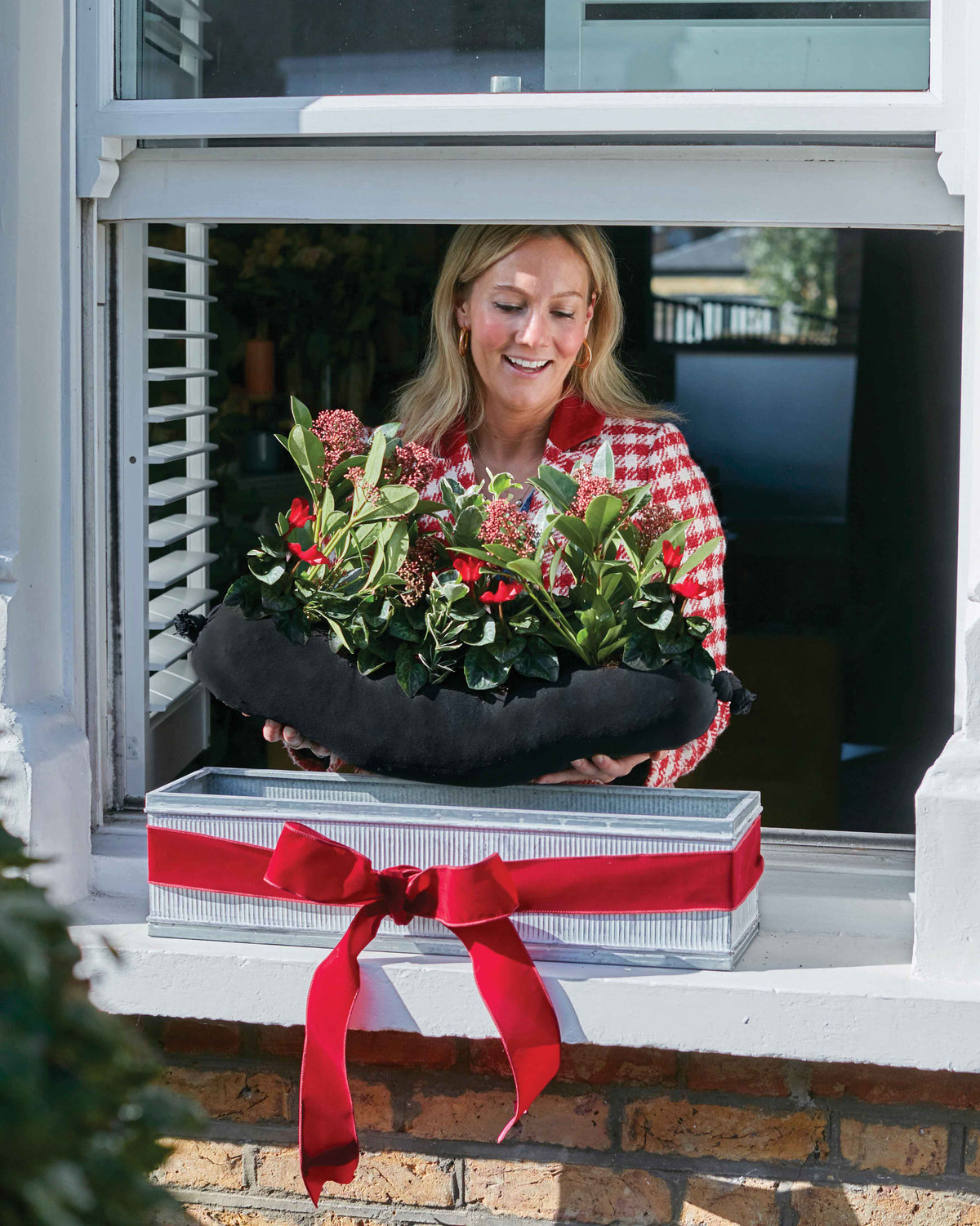 Woman placing planted plants in a window box